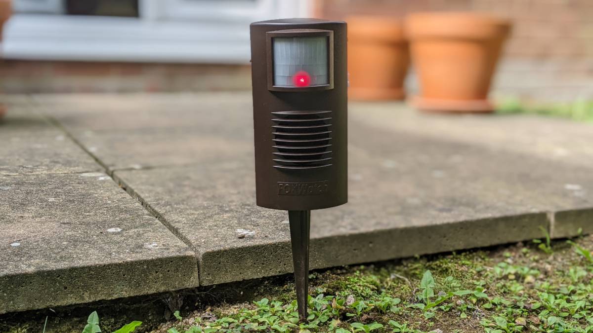 A FOXWatch Ultrasonic Deterrent device in front of a patio in a garden.